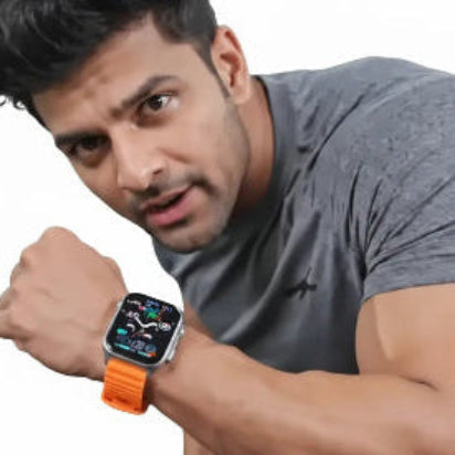 Man in a gym looking at an orange smartwatch